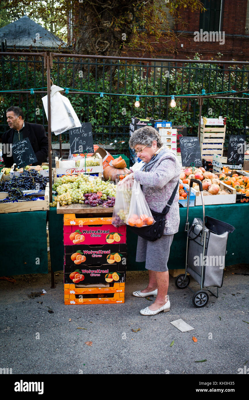 Una donna anziana che acquista in un negozio di frutta e verdura nel mercato domenicale del piccolo villaggio di Darnetal vicino Rouen in Francia. Foto Stock