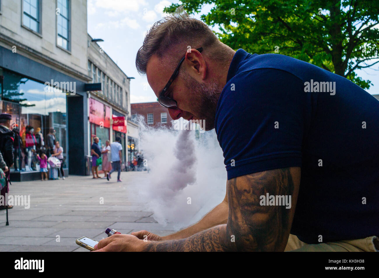 Un uomo studia il suo telefono cellulare mentre vaporava per strada. Foto Stock