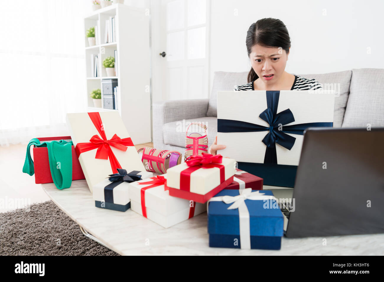 Giovane ragazza dolce guardando confezione regalo sentirsi confuso quando lei usa il computer per lo shopping online e ricevuto estate stagione di vendita presenti in casa. Foto Stock