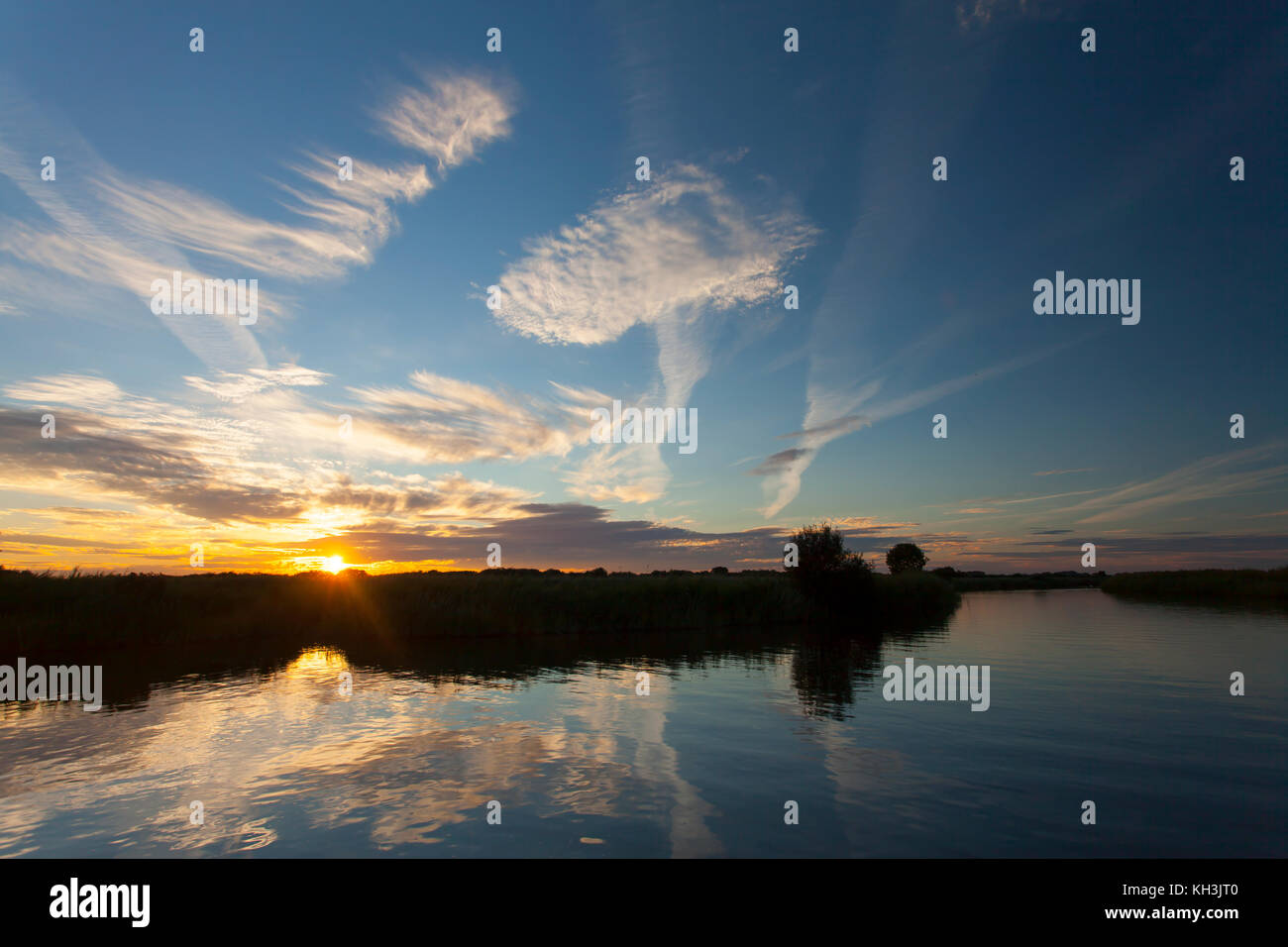 Tramonto sulla flotta dike, vicino a South walsham ampio e il fiume bure sul Norfolk Broads. alto nuvole e tramonto riflesso nella calma, ancora nelle acque del fiume Foto Stock