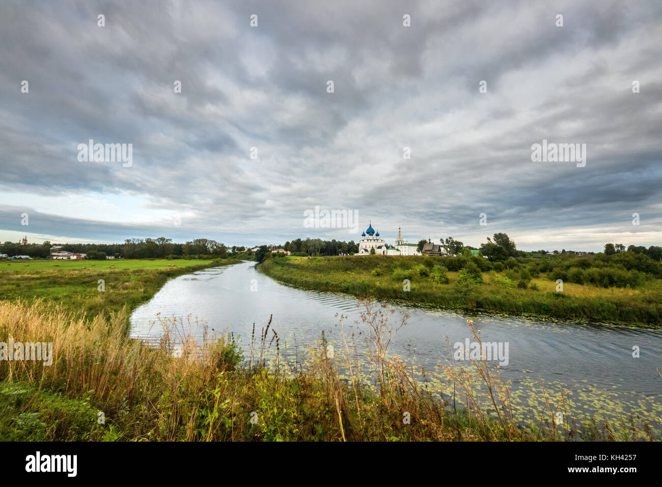 Vista di Suzdal, con campi verdi, il fiume Reka e kamenka il Cremlino di Suzdal sotto un drammatico cielo nuvoloso, suzdalsky distretto, golden ring, Russia. Foto Stock