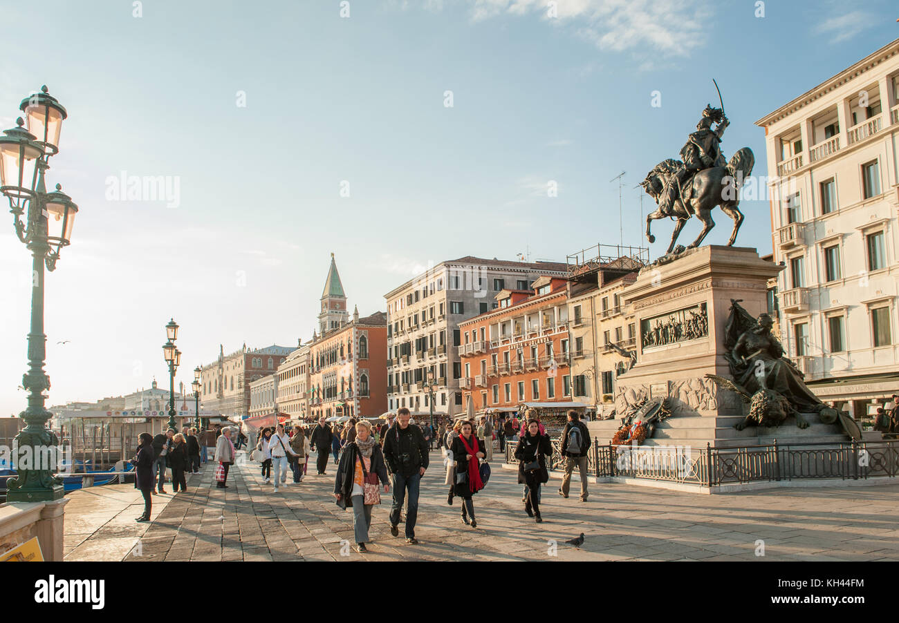 I turisti si godono una passeggiata sul lungomare Riva degli Schiavoni a San Marco. Venezia è una delle principali destinazioni turistiche in Italia. Foto Stock