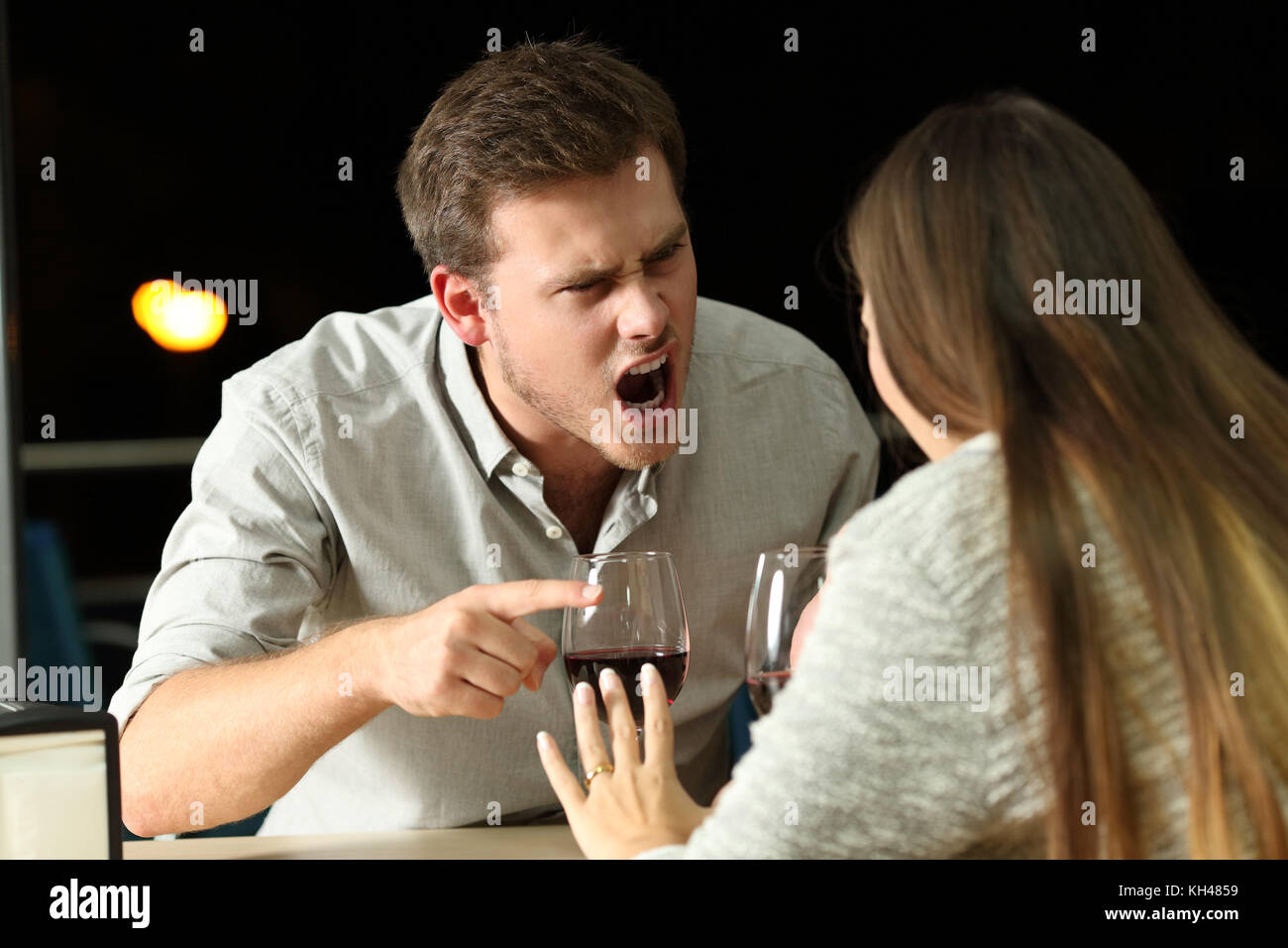 Arrabbiato giovane litigare furiosamente in un bar di notte Foto Stock