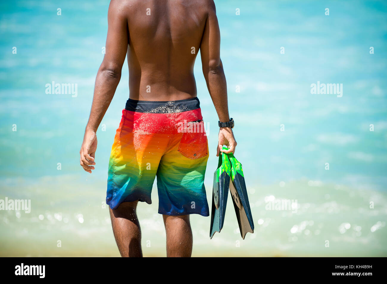 Irriconoscibile giovane brasiliano corpo surfer camminare con le sue alette lungo il litorale di arpoador Beach, il popolare surf break in rio de janeiro, Brasile Foto Stock