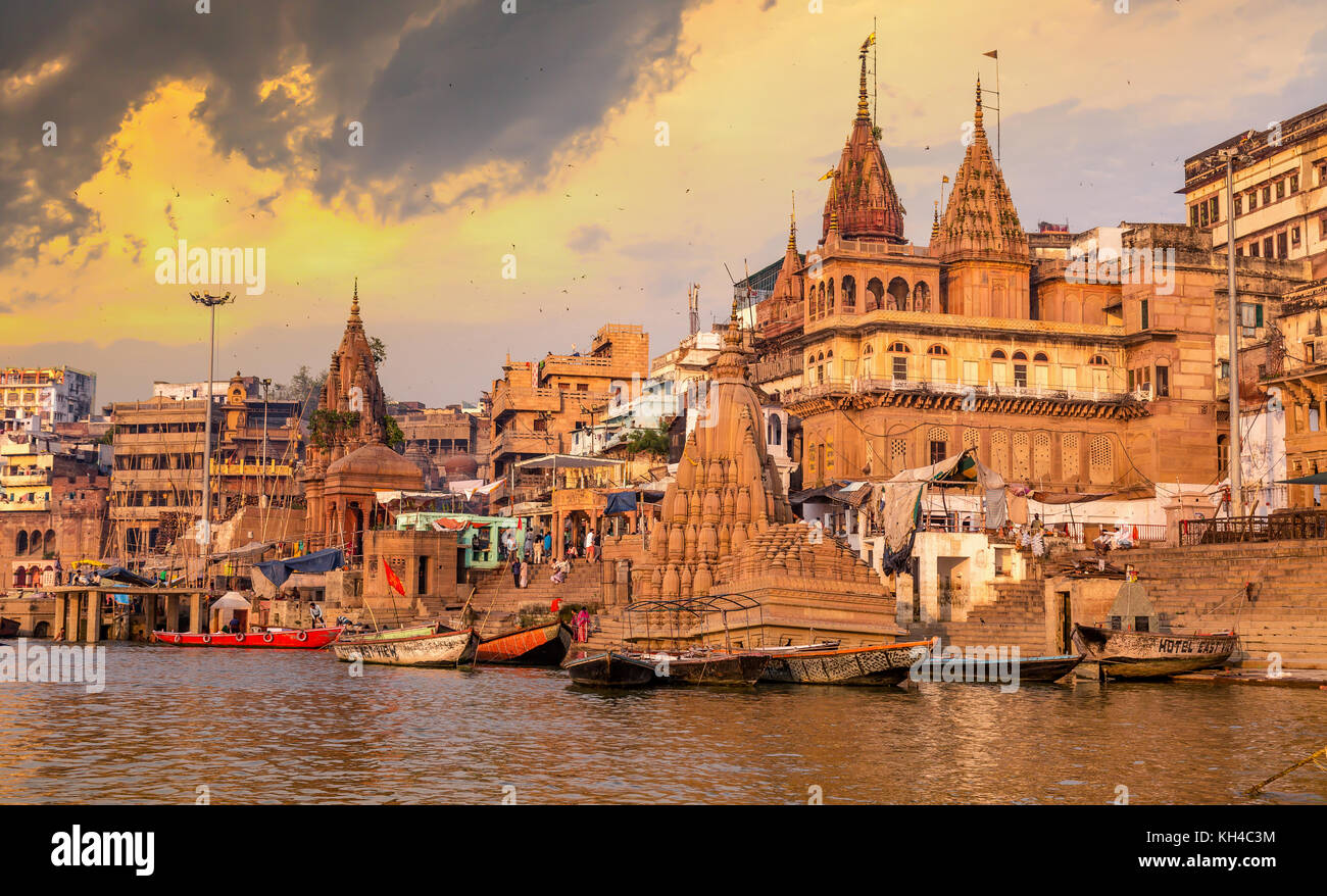 Varanasi città di antica architettura edifici lungo il fiume Gange ghat al tramonto con moody sky. Foto Stock