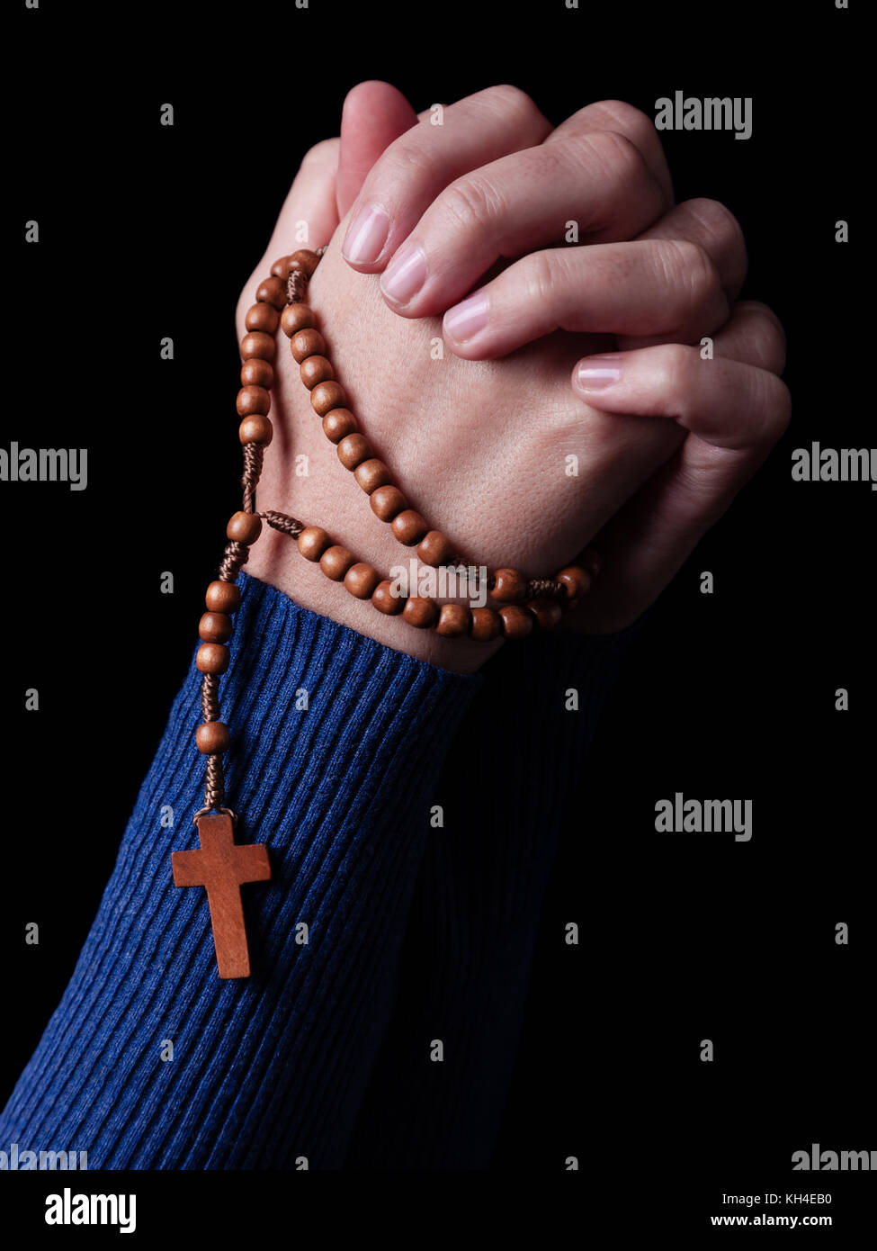 Mani femminili pregando tenendo un rosario con Gesù Cristo in croce o crocifisso su sfondo nero. donna con cristiana cattolica fede a mano Foto Stock