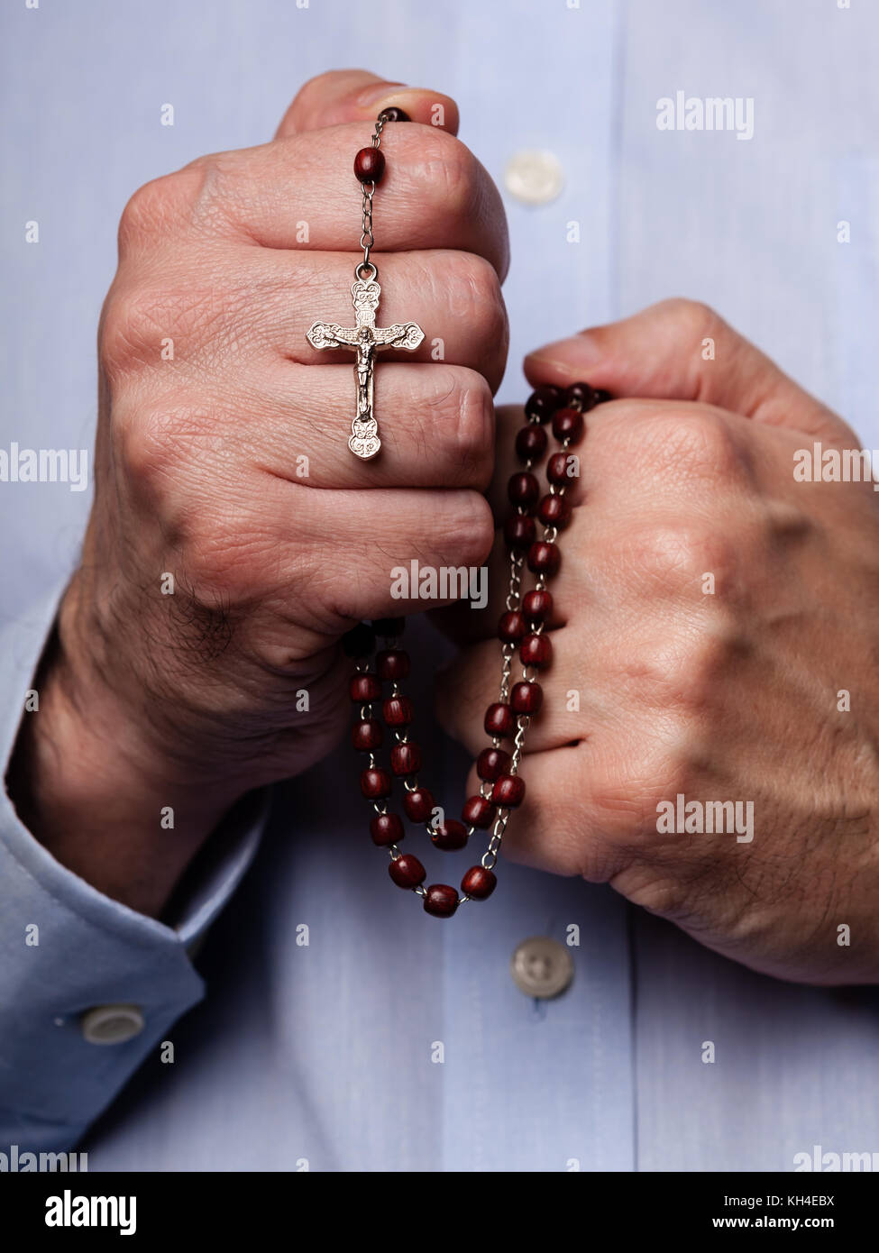 Mani maschio pregando tenendo un rosario con Gesù Cristo in croce o crocifisso su sfondo nero. uomo maturo con cristiana cattolica fede religiosa Foto Stock