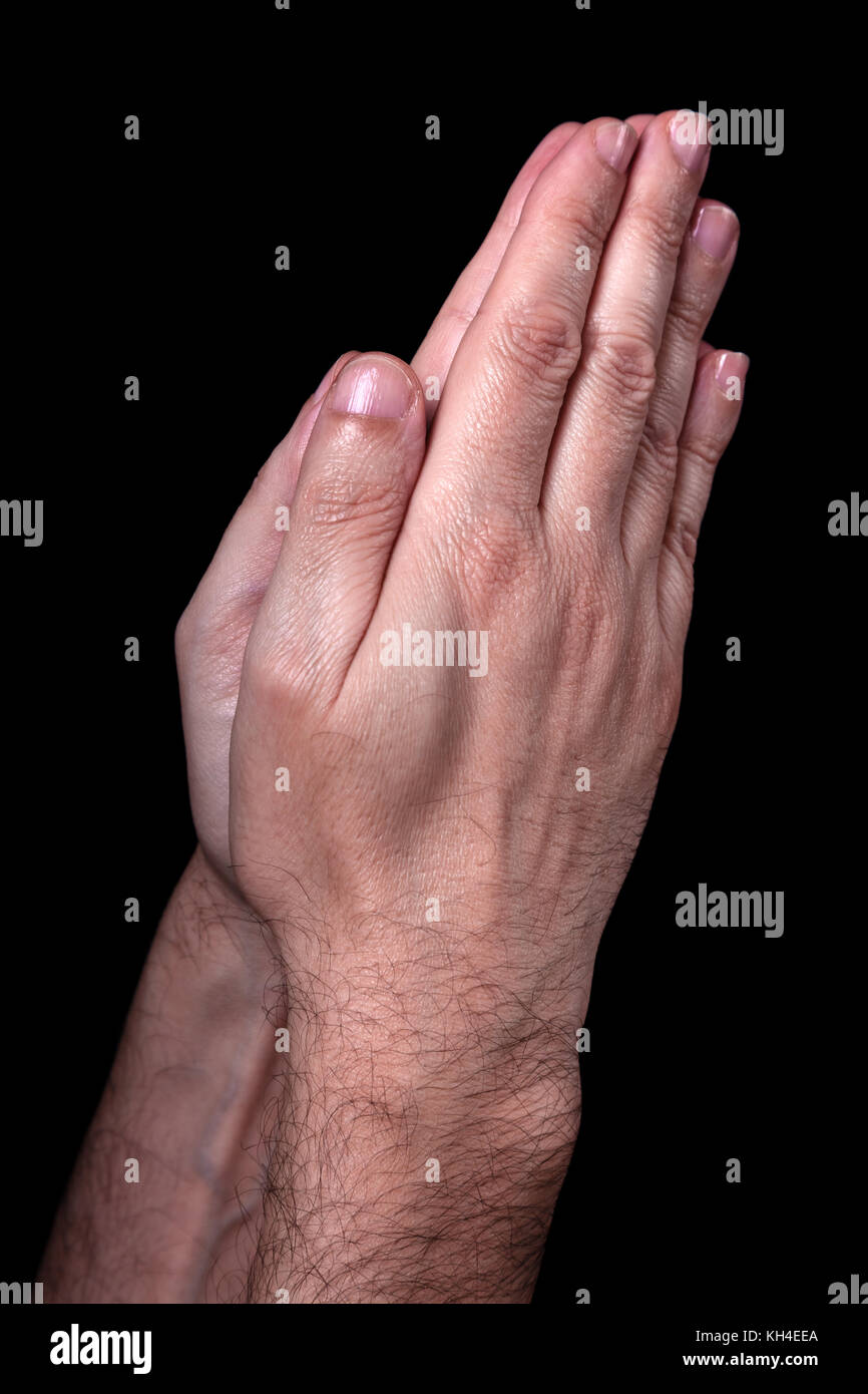 Mani maschio pregando con palme insieme. sfondo nero. close up man mano. concetto di preghiera, di pregare, di fede e di religione, religiosi, di culto Foto Stock