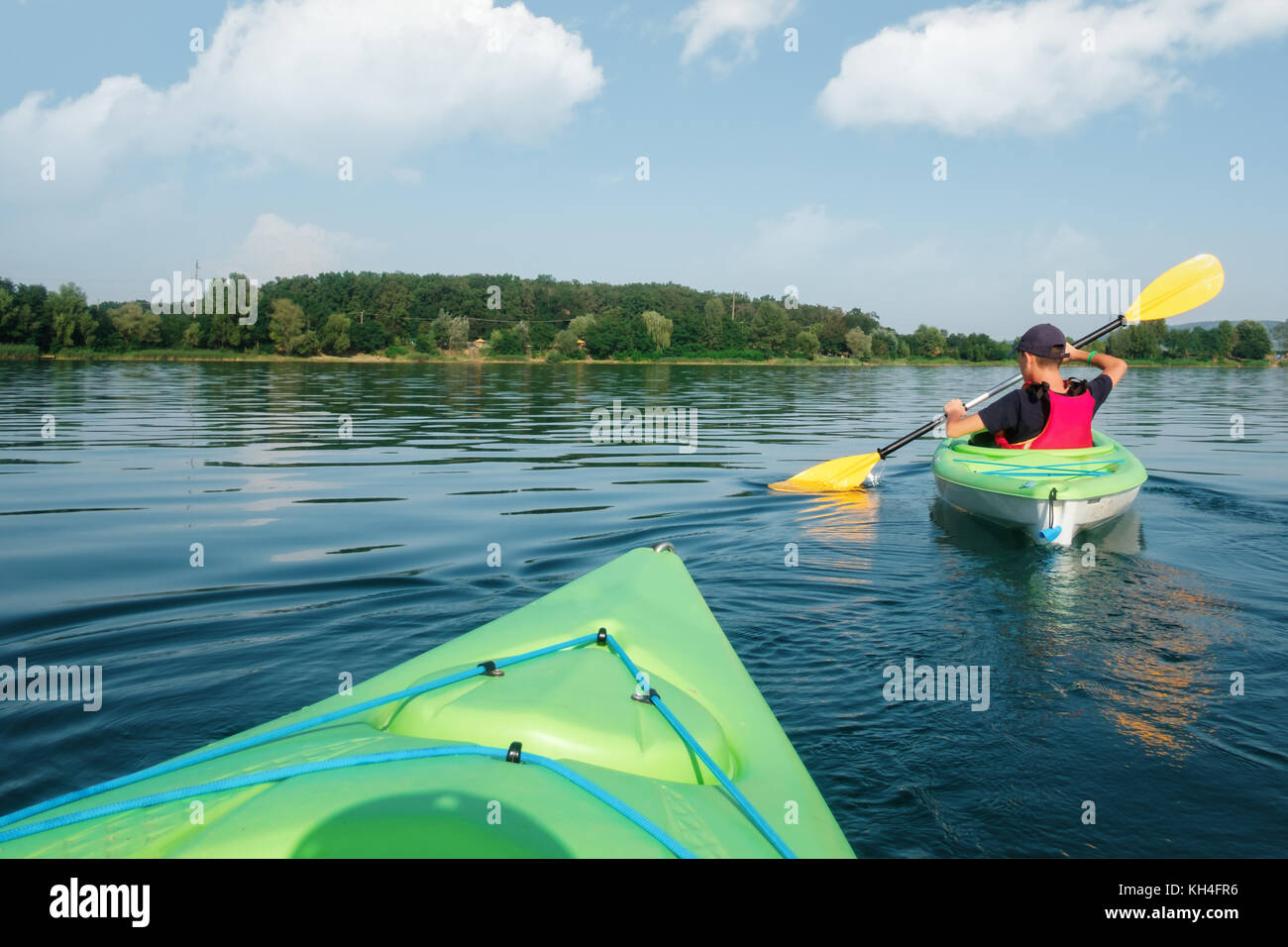 Ragazzo in vita giacca verde sul kayak Foto Stock