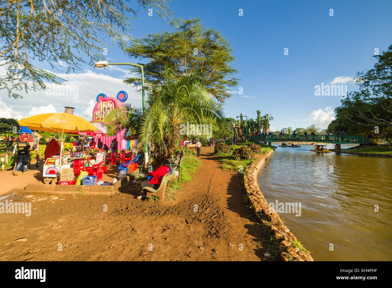 Bambini giostre come pure la gente camminare attraverso Uhuru Park dal lago in barca nel tardo pomeriggio di luce, Nairobi, Kenia Foto Stock
