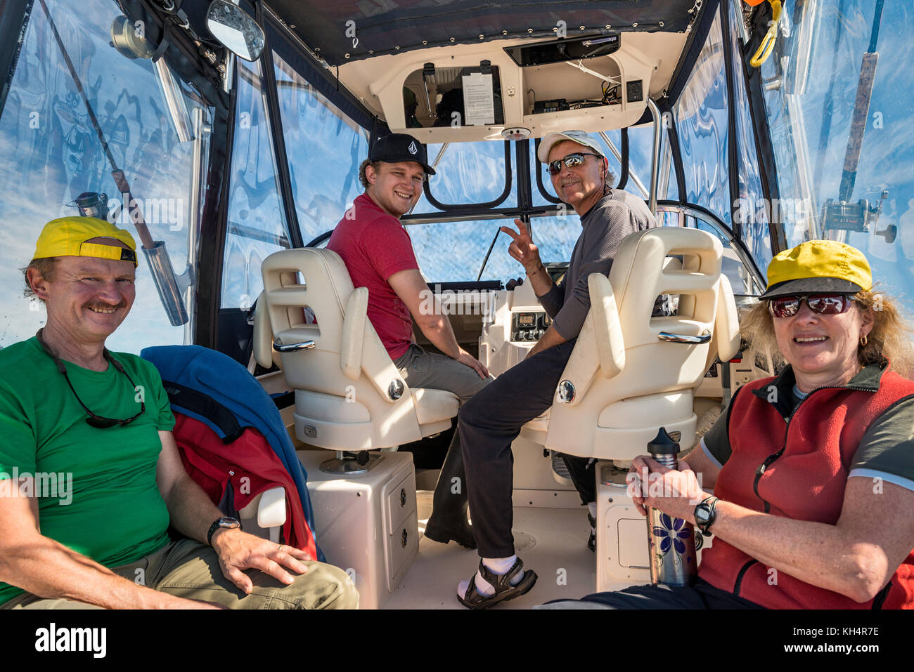 Quattro persone sedute a bordo di un motoscafo, che ritornano da un viaggio di pesca, sorridendo, guardando la macchina fotografica, Vancouver Island area, British Columbia, Canada Foto Stock