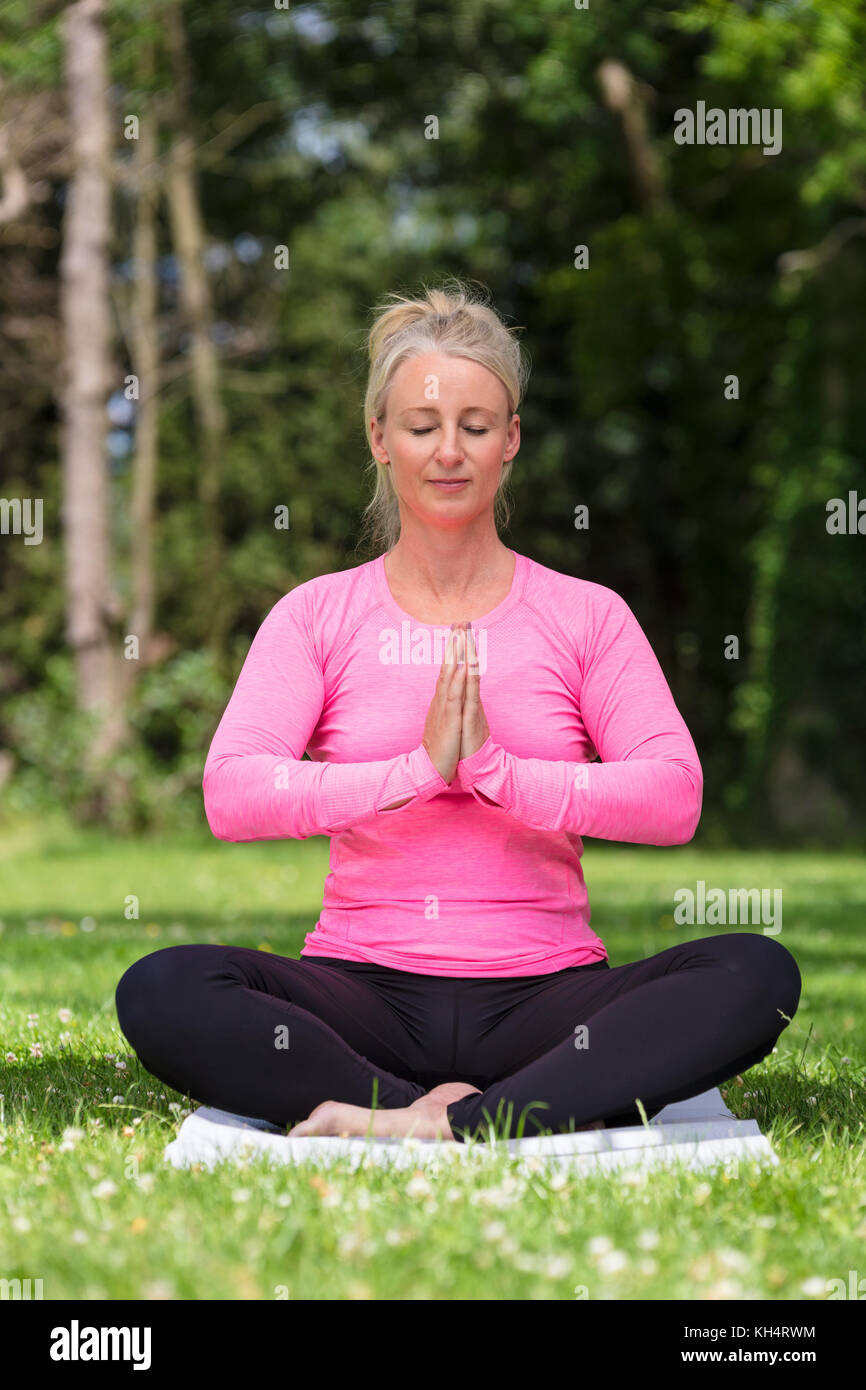 Coppia di mezza età montare donna sana pratica lo yoga al di fuori di una naturale tranquillo ambiente verde Foto Stock