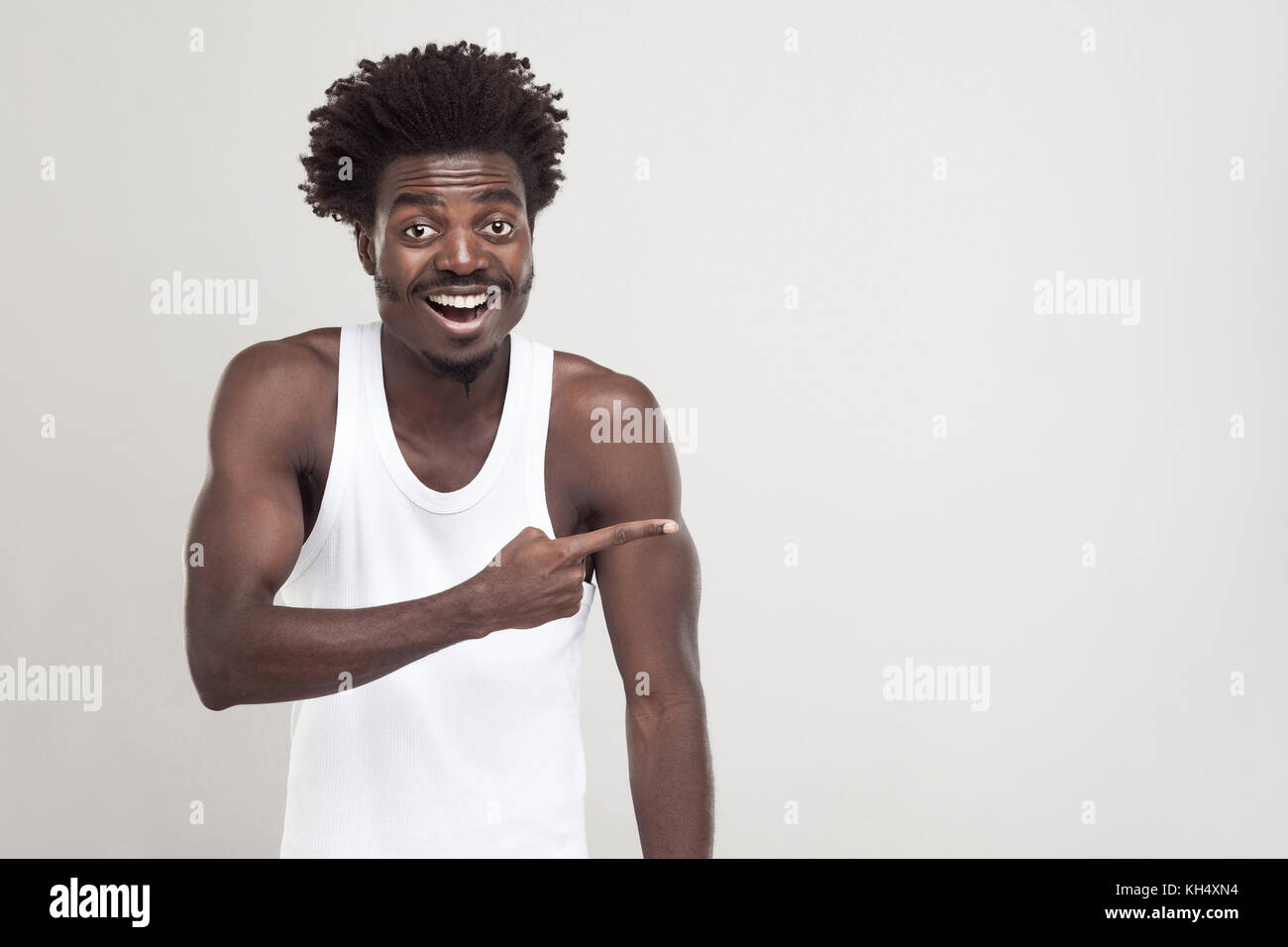 Lo stupore afro uomo, puntare il dito a copiare lo spazio. studio shot. sfondo grigio Foto Stock