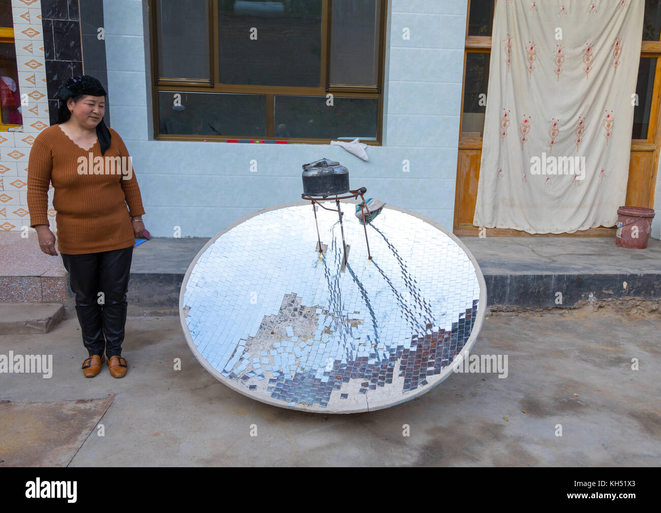 Salar minoranza etnica donna di fronte a energia solare cookery usato per bollire acqua, Provincia di Qinghai, Xunhua, Cina Foto Stock