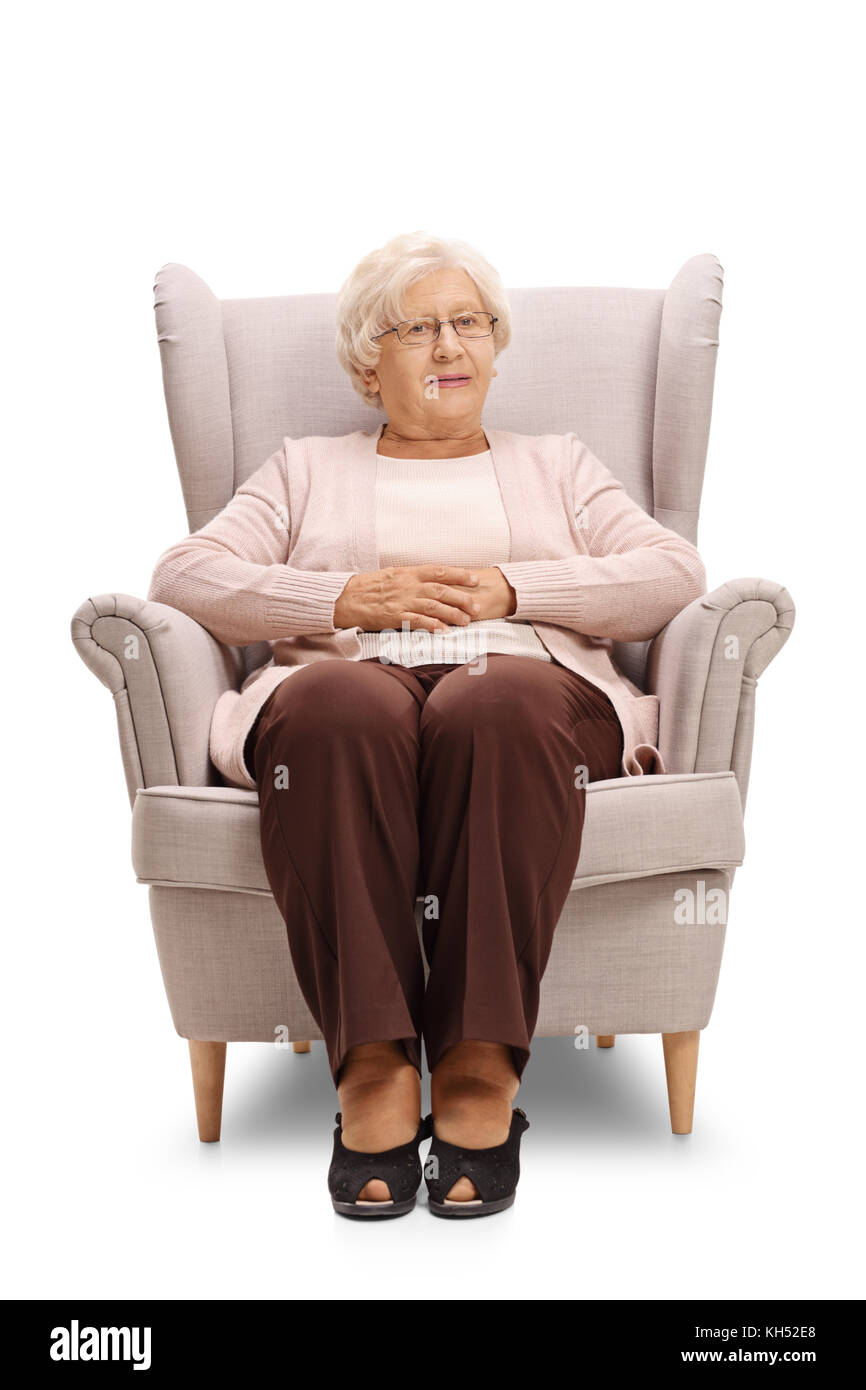 Donna anziana seduti in poltrona e guardando la telecamera isolata su sfondo bianco Foto Stock