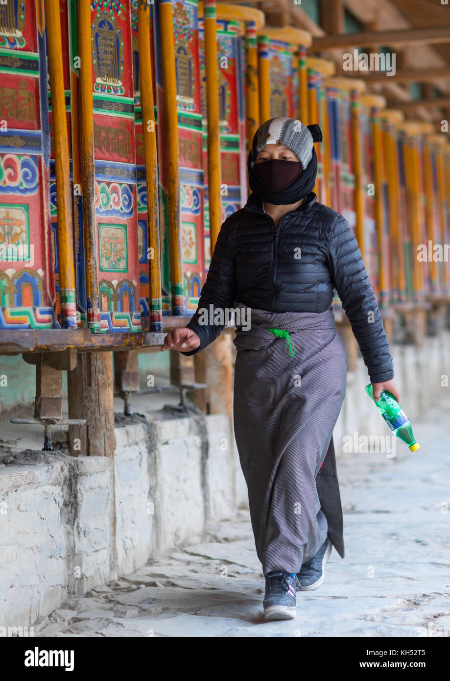 Pellegrino tibetano girando enormi ruote della preghiera nel monastero di Labrang, provincia di Gansu, Labrang, Cina Foto Stock