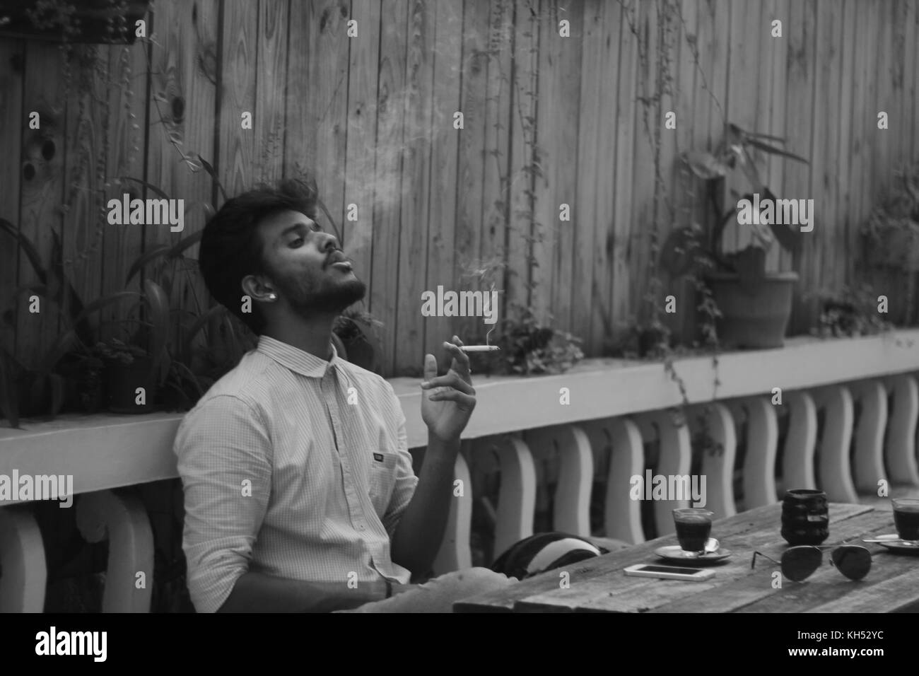 Un ragazzo indiano di fumare una sigaretta in un cafe Foto Stock
