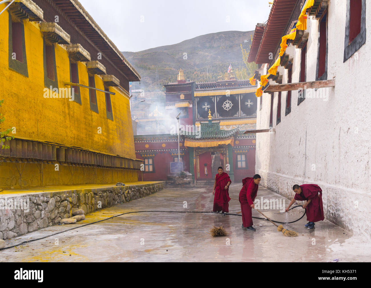 I monaci buddisti in rosso accappatoi pulizia del monastero di Rongwo, Tongren County, Longwu, Cina Foto Stock