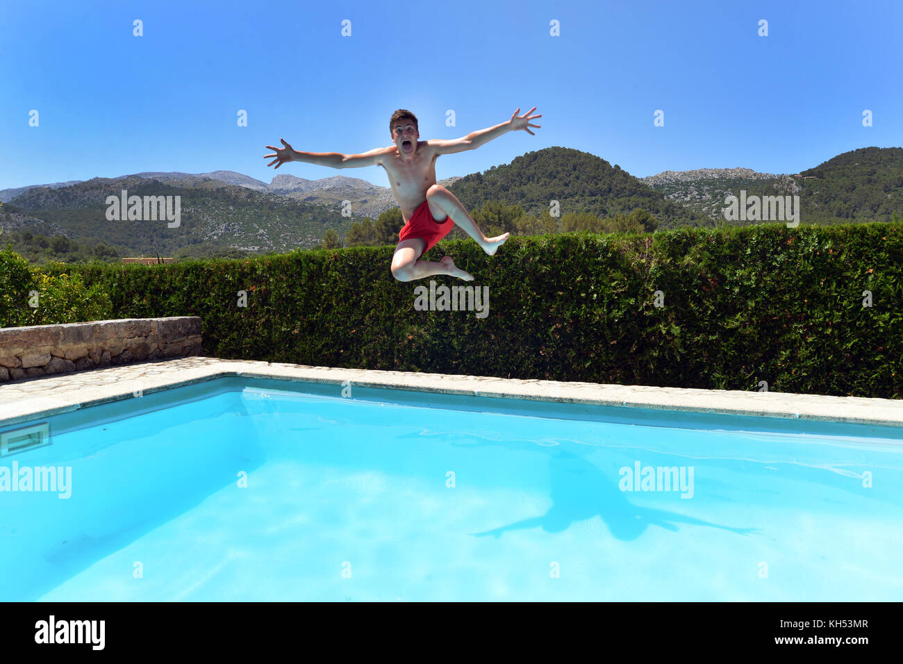 Ragazzo adolescente salto in una villa privata e piscina Foto Stock