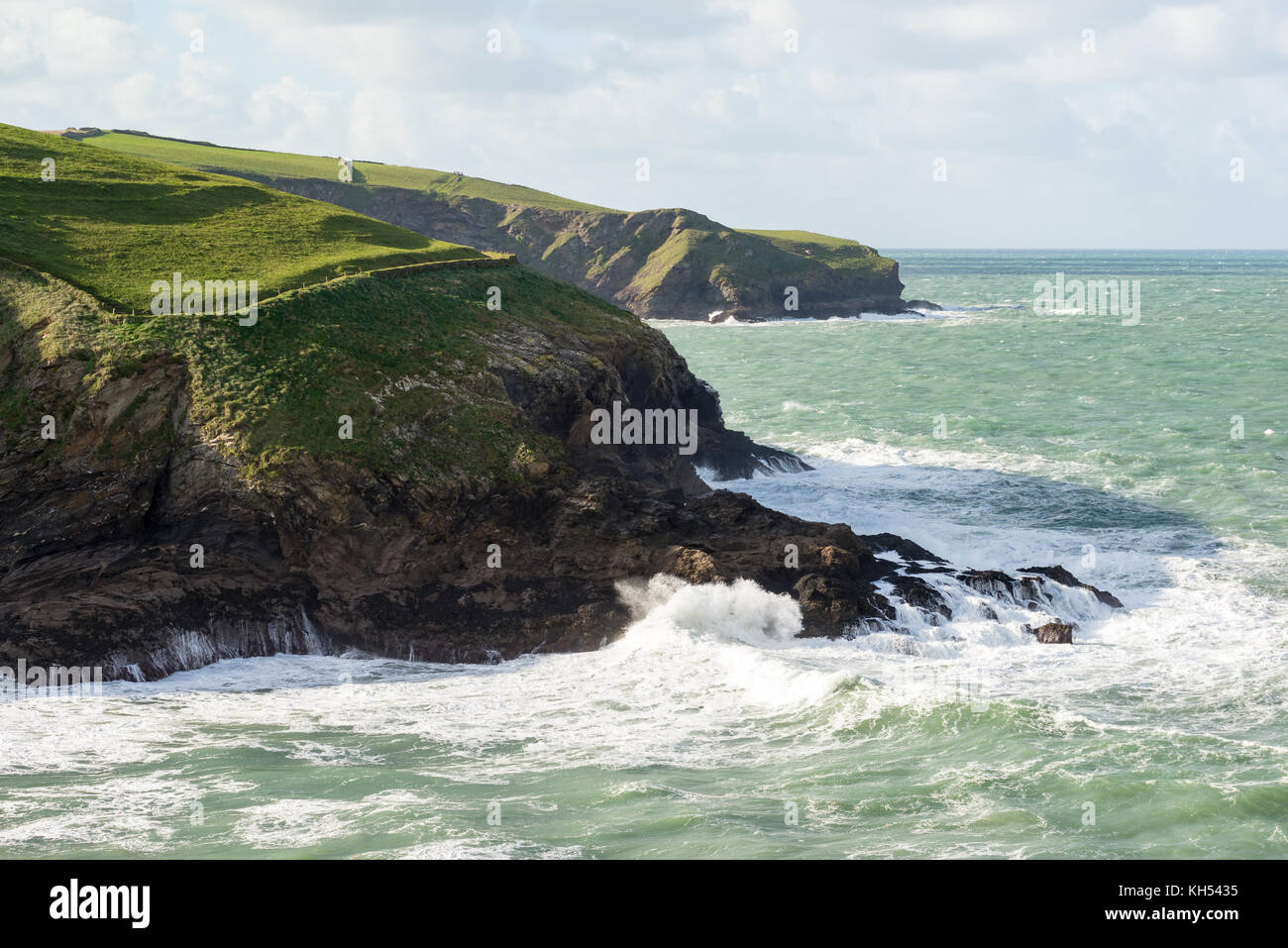 Un mare increspato invia onde si infrangono contro gli scogli vicino a Port Isaac sulla North Cornwall coast, UK, su una soleggiata giornata autunnale. Foto Stock