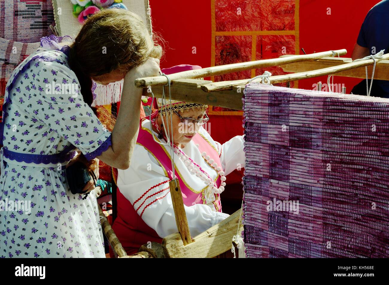 04.07.2015.Russia.San Pietroburgo.Festival dei maestri. Una donna tesseva un tappeto come facevano ai vecchi tempi. Foto Stock