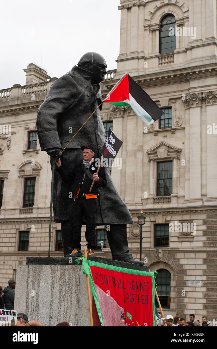 Un manifestante si erge sulla base di Churchill e sventola la bandiera palestinese, Parliament Square, Londra. Foto Stock