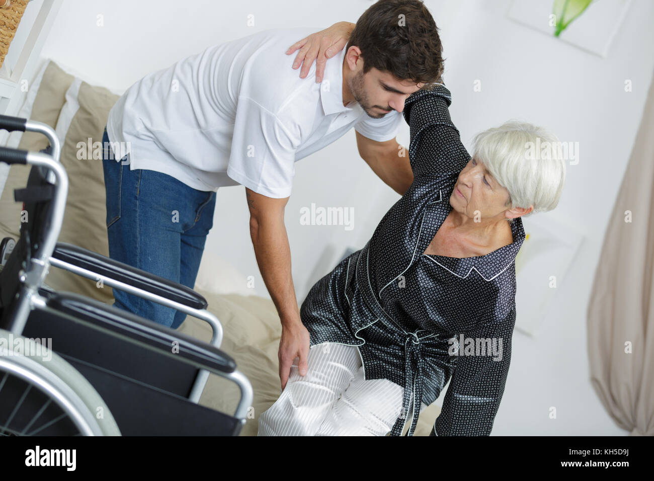 L'infermiera aiutando disabilitato signora seduta sulla sedia a rotelle Foto Stock