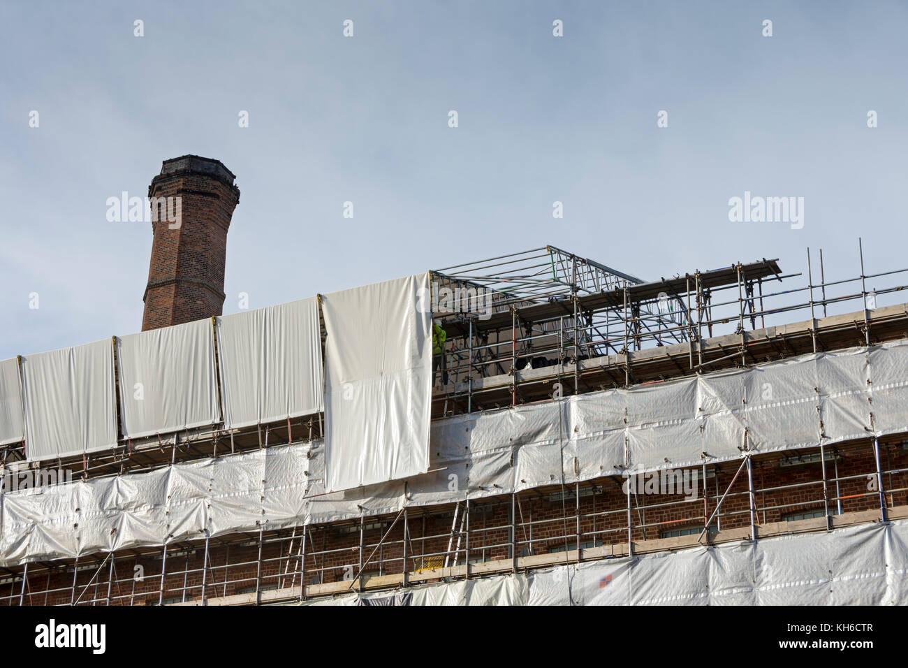 Operai che rimuovono i fogli da un tetto temporaneo al Murrays' Mills Complex, in fase di conversione in appartamenti, Ancoats, Manchester, Inghilterra, Regno Unito Foto Stock