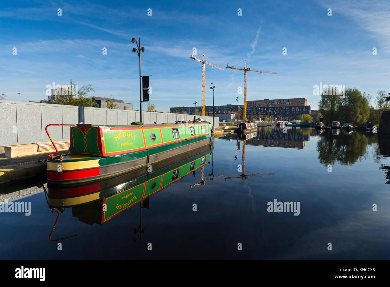 Un narrowboat e gru sul sito delle tessitrici Quay development (appartamenti), che si riflette nel campo di cotone Park marina, Ancoats, Manchester, Regno Unito Foto Stock