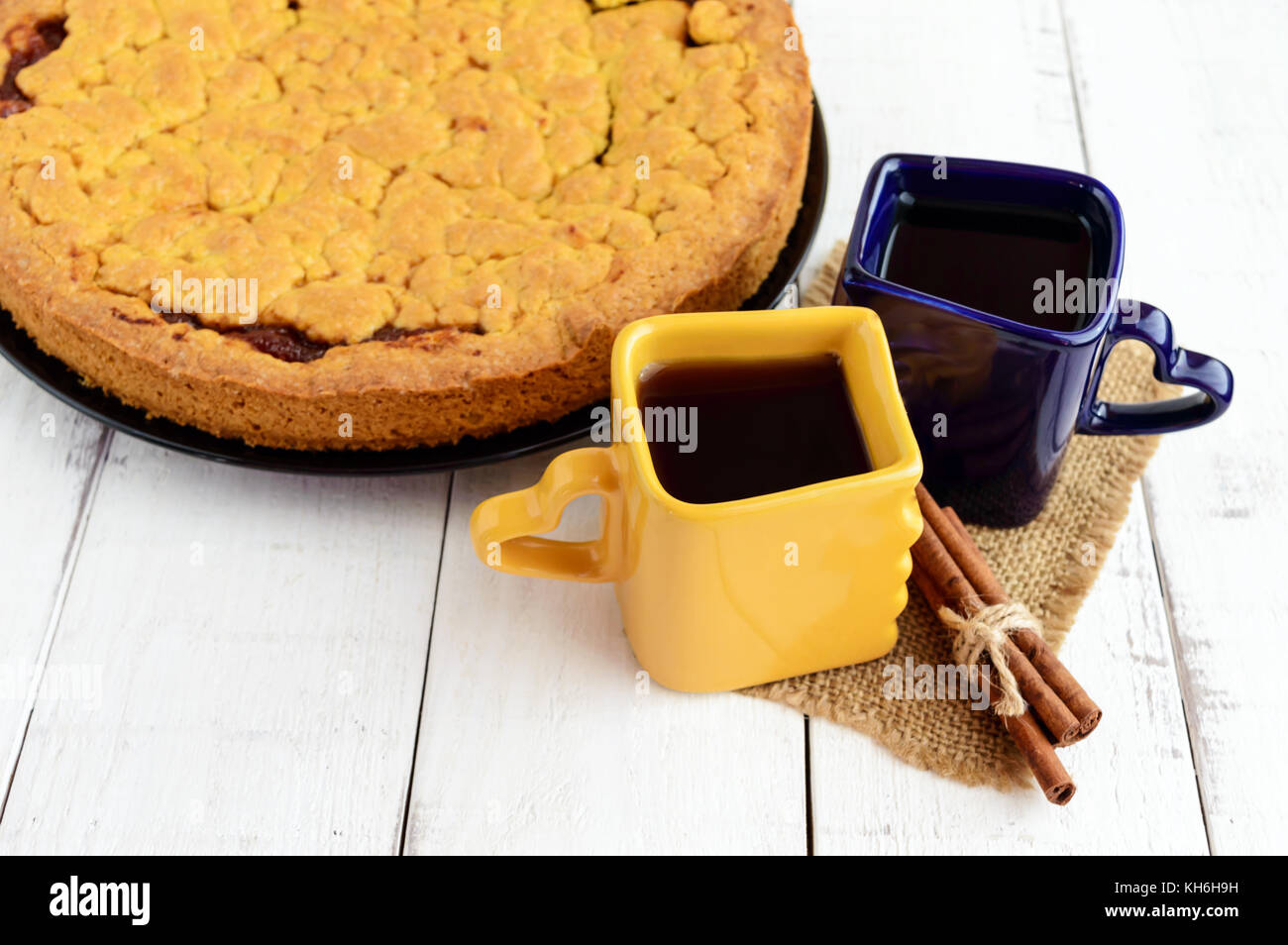 Due belle coppe (blu scuro e giallo) con caffè, tè e pane appena sfornato dolci fatti in casa con confettura di albicocca. Foto Stock