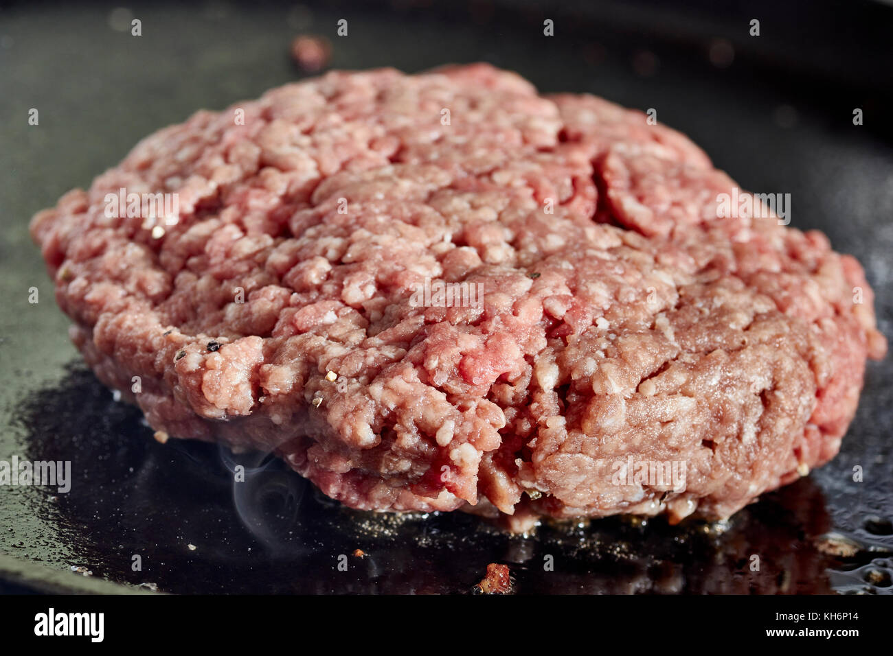 Un hamburger patty la frittura su una griglia in ghisa Foto Stock