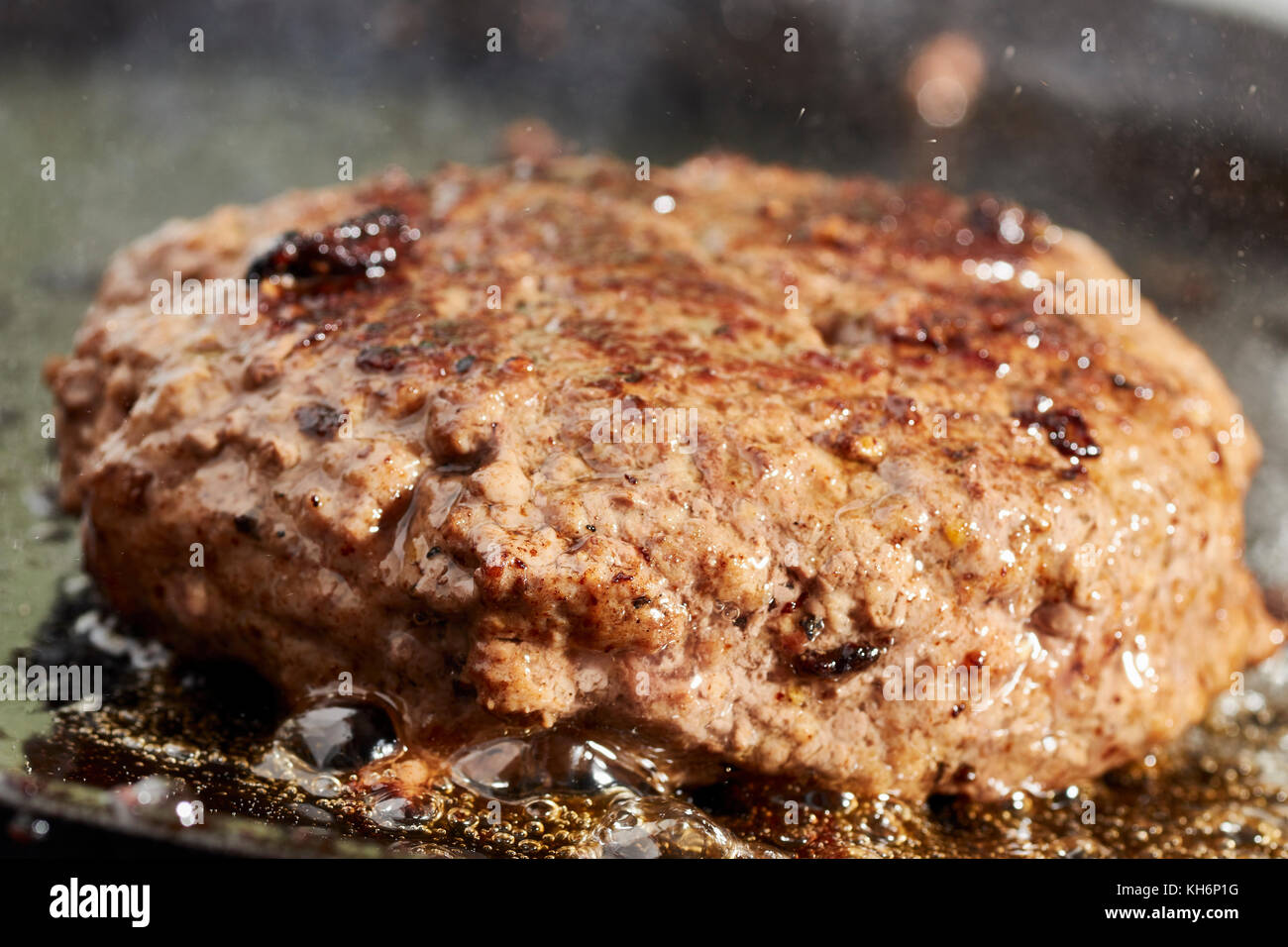 Un hamburger patty la frittura su una griglia in ghisa Foto Stock