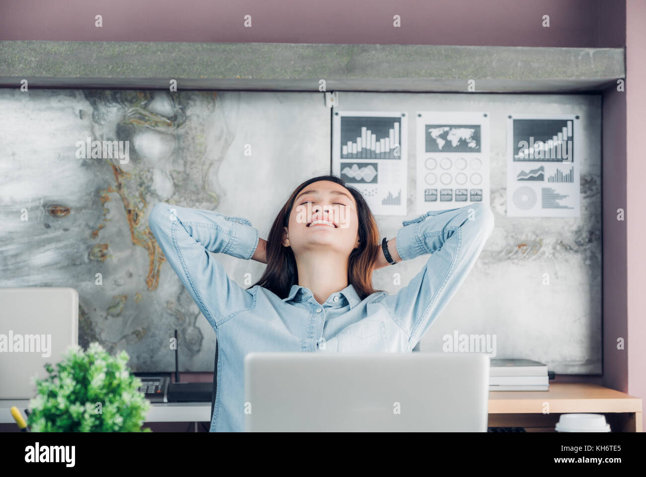 Asian creative designer sollevare il braccio e il resto in corrispondenza della parte posteriore della testa e chiudere gli occhi di fronte a computer laptop sulla scrivania,relax dal duro lavoro in ufficio. Foto Stock