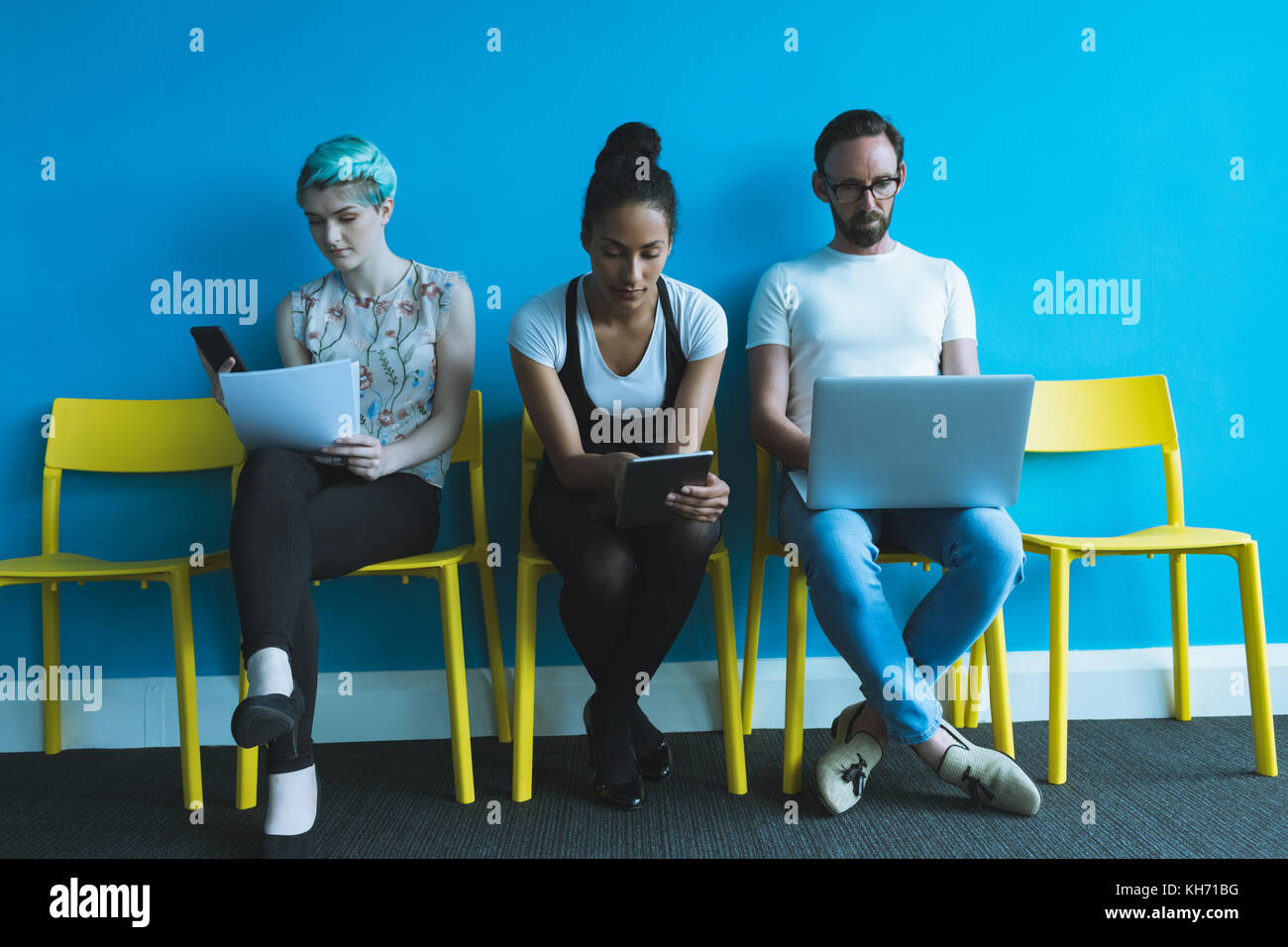 I dirigenti seduti su una sedia e utilizzo di gadget elettronici in office Foto Stock