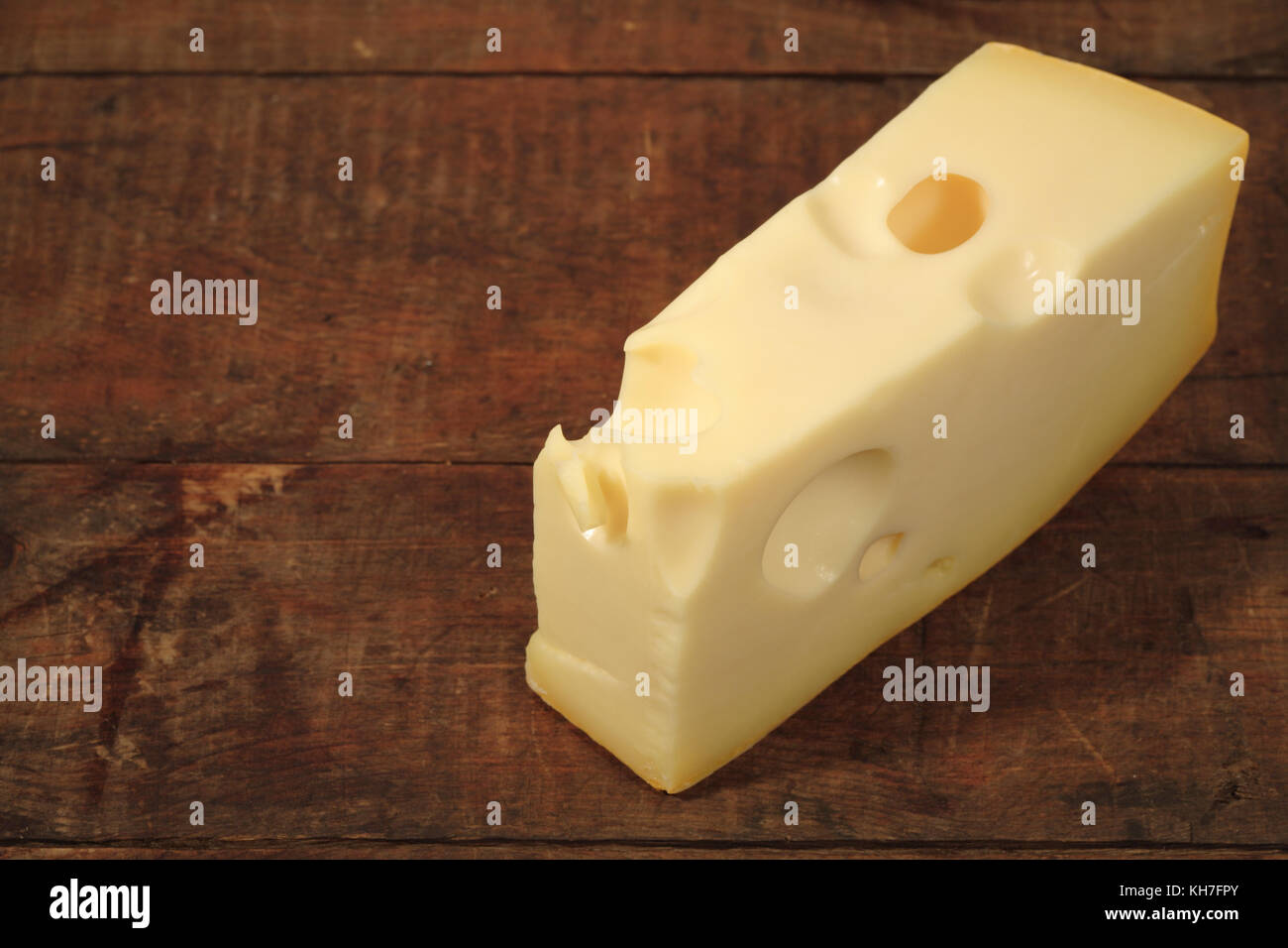 Un pezzo di formaggio giacente su sfondo di legno con spazio di copia Foto Stock