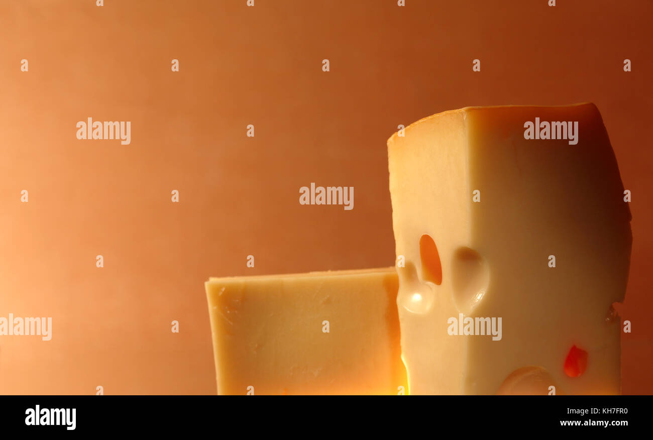 Due pezzi di formaggio contro gradiente colorato sfondo con spazio di copia Foto Stock