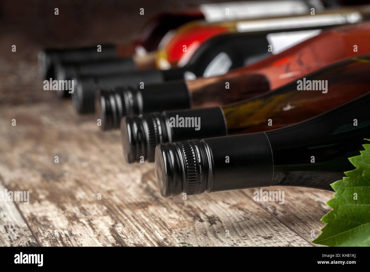 Le bottiglie di vino impilati su un tavolo di legno shot con limitata profondità di campo Foto Stock
