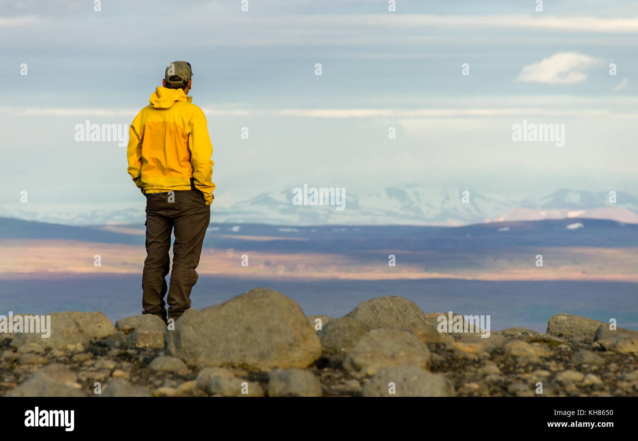 Uomo in piedi sulla montagna, guardando rilassato verso la montagna innevata gamma. Foto Stock