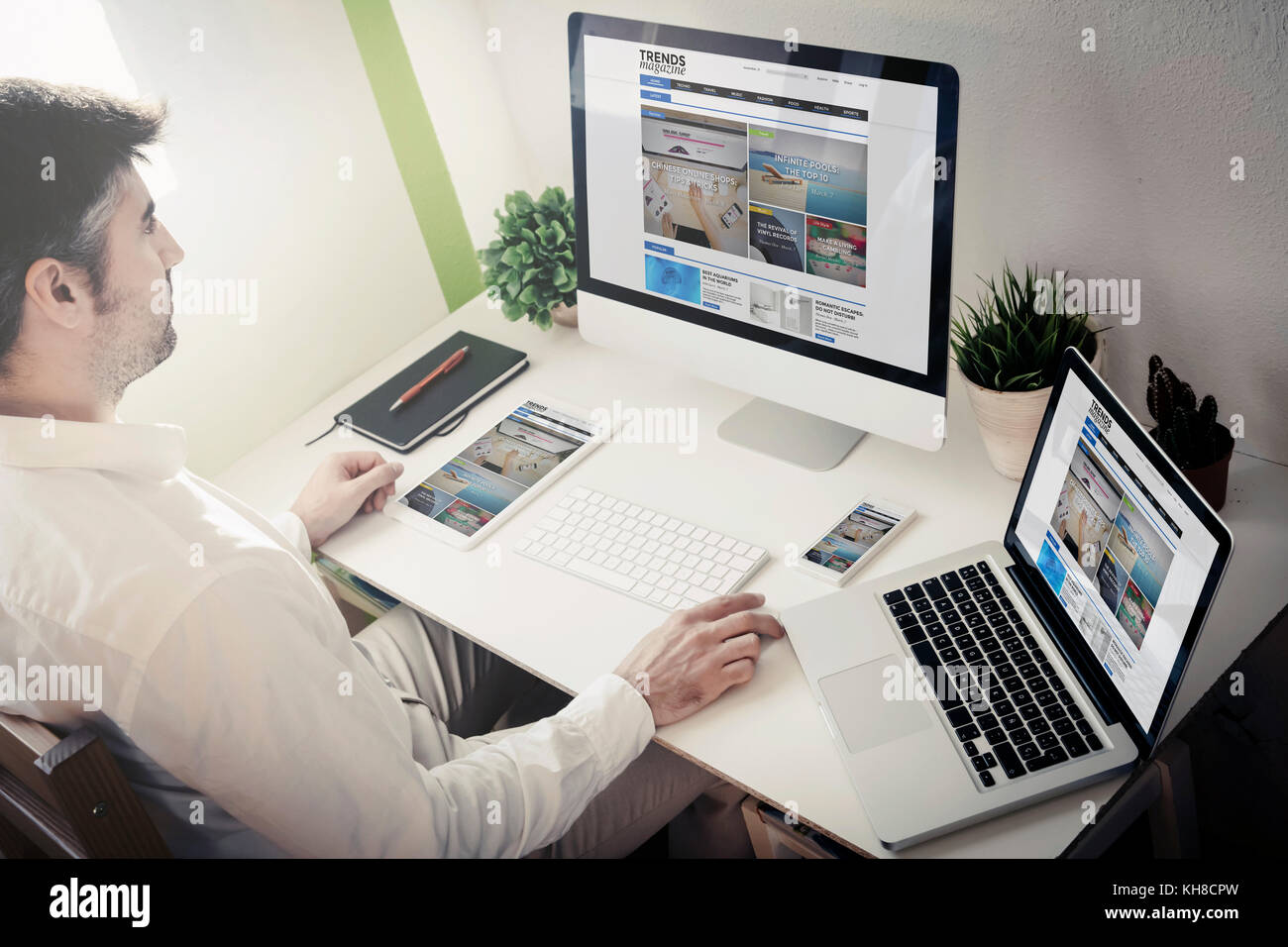 L'uomo navigando in internet con i dispositivi con blog sito web magazine. Tutti i grafici dello schermo sono costituiti. Foto Stock