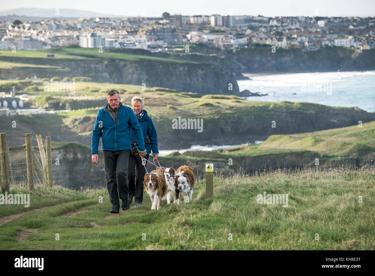 Due persone che camminano i loro cani animali domestici lungo la costa sud-ovest percorso in Newquay Cornwall Regno Unito. Foto Stock
