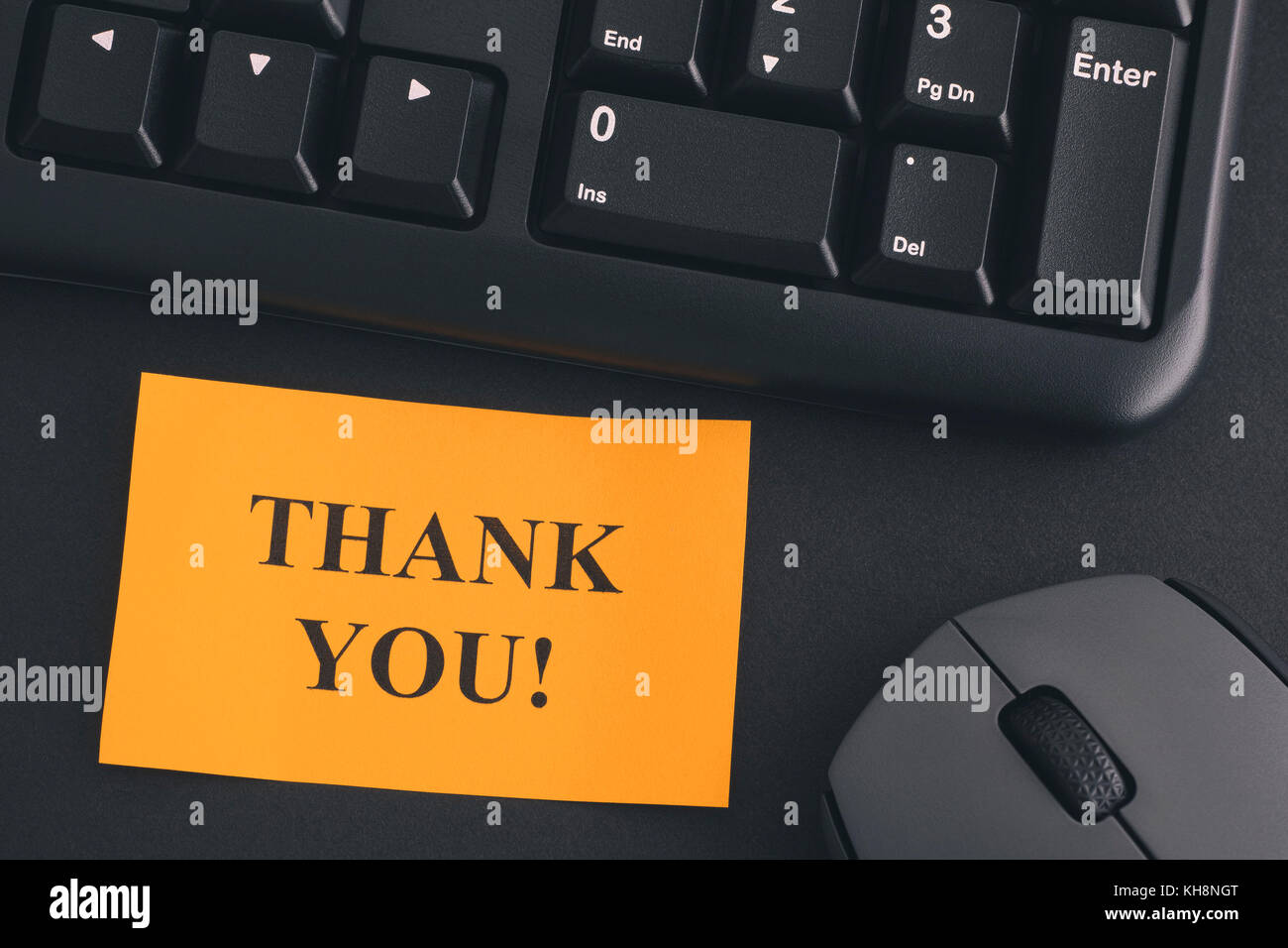 Grazie!. carta nota con la scrittura grazie! Su una scrivania con tastiera nera e grigia mouse wireless. close up. Foto Stock