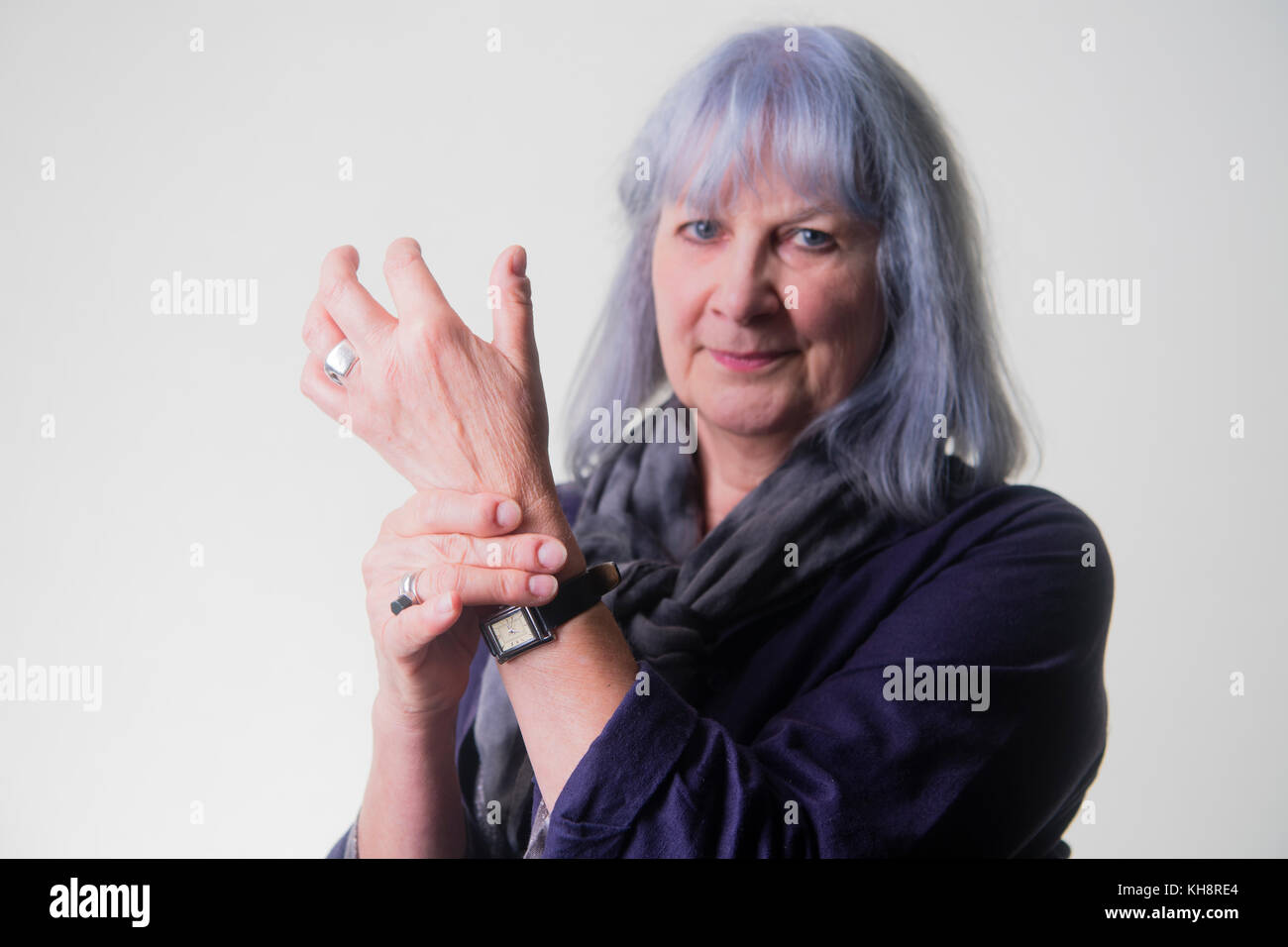 Un pelo grigio senior adulto donna anziana nonna, strofinando il polso artritiche, Regno Unito Foto Stock