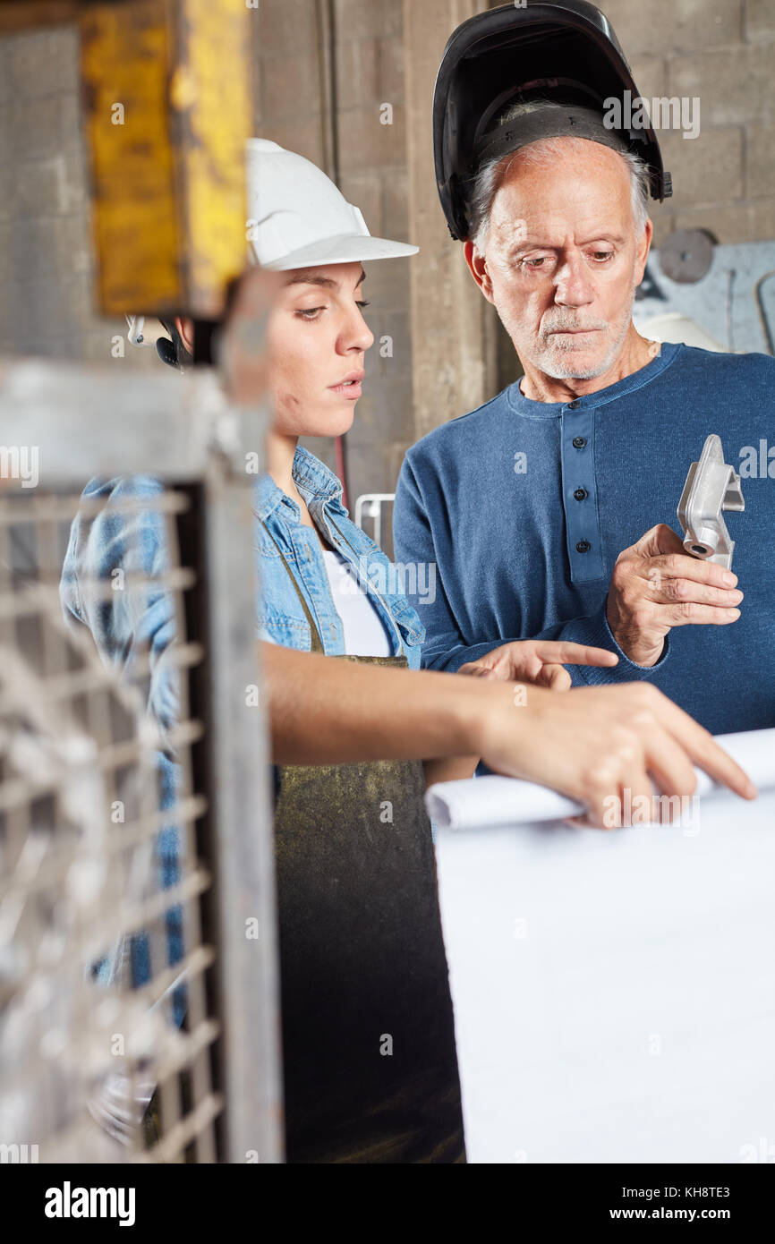 Senior come carpentiere metallico e giovane collega la pianificazione della produzione in riunione Foto Stock