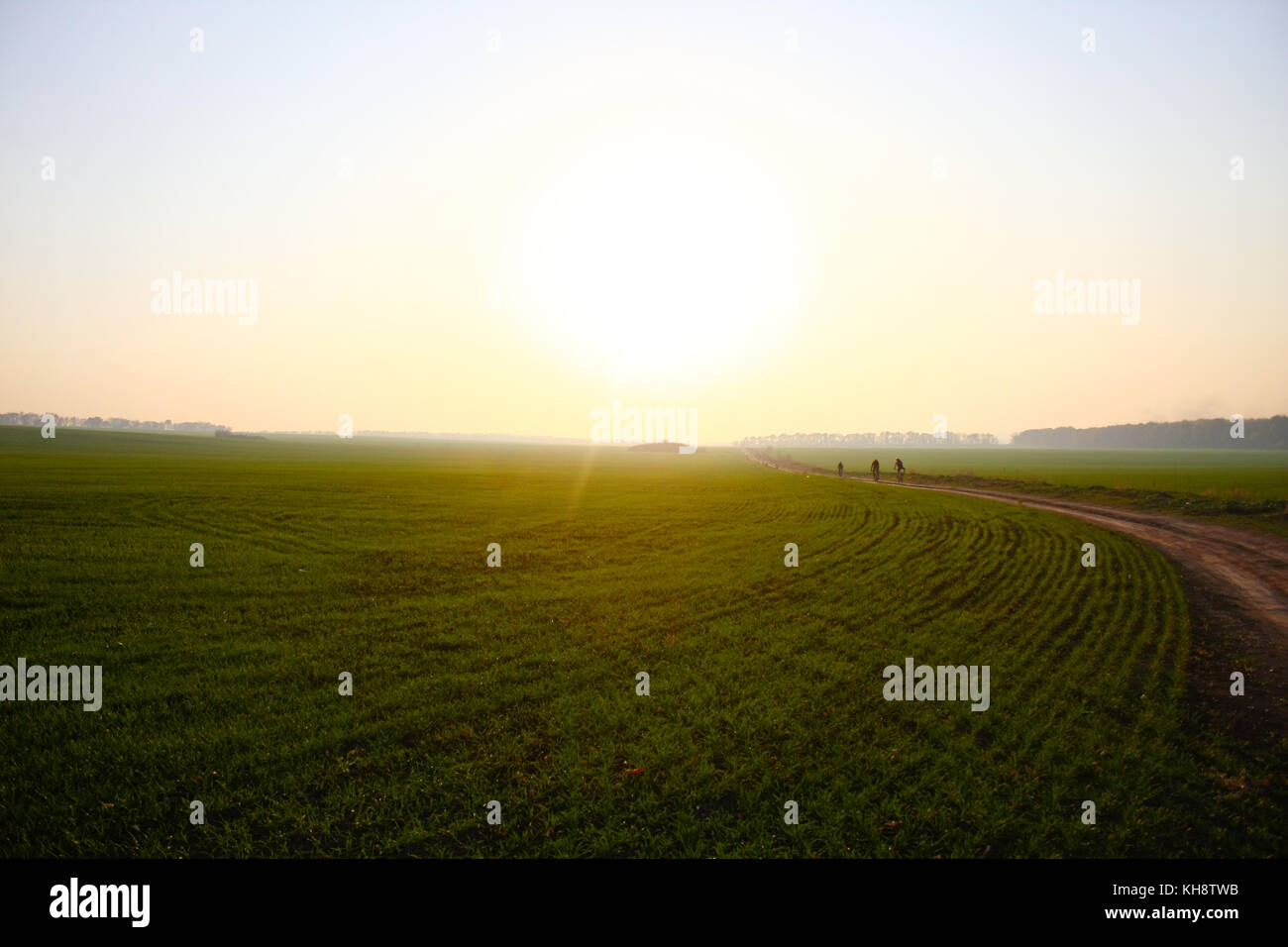 Tre ciclista cavalcare la loro moto in un campo aperto al tramonto in autunno Foto Stock