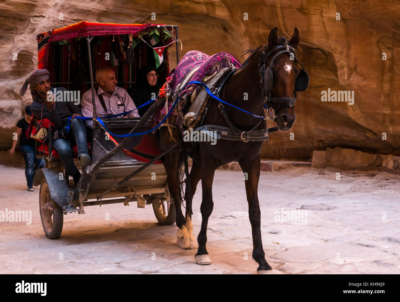 Un cavallo e carrozza di prendere i turisti attraverso il mezzogiorno ombra della gola di Siq, Petra, Giordania, Medio Oriente Foto Stock