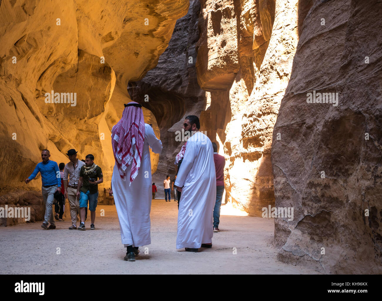 Due uomini arabi in tradizionali vesti bianche, jubbahs, e copricapo a piedi attraverso la gola di Siq, Petra, Giordania, Medio Oriente Foto Stock