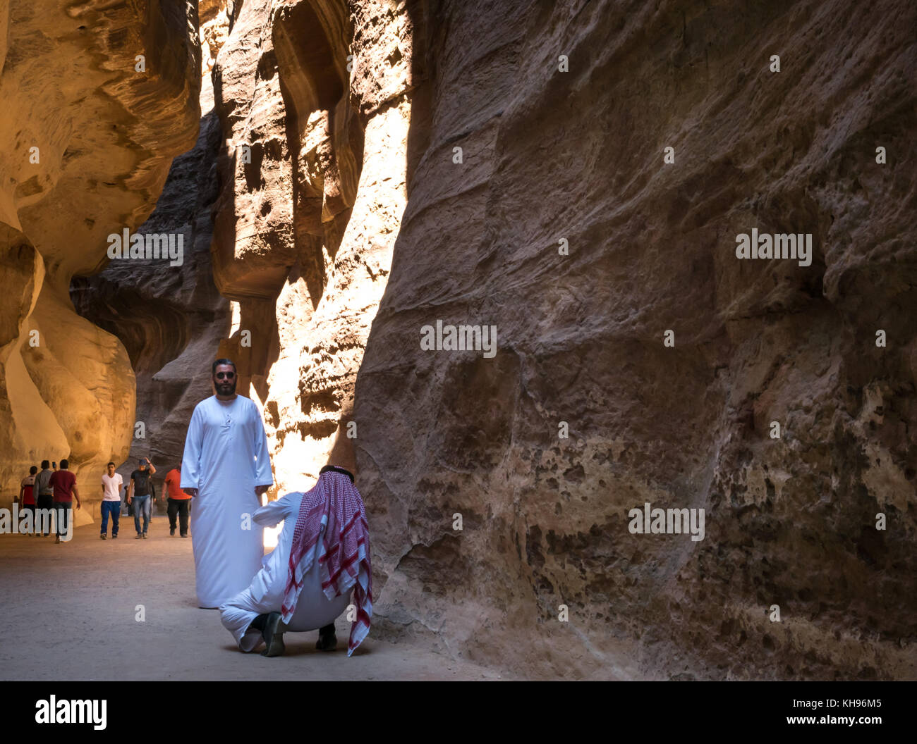 Uomo arabo nella tradizionale tunica bianca e testa kufiya abito di scattare una foto nella gola di Siq, Petra, Giordania, Medio Oriente Foto Stock