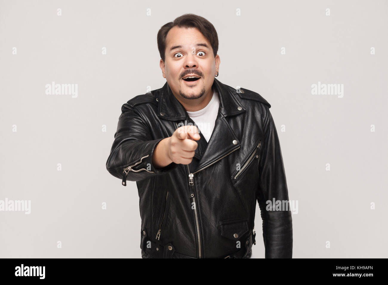 L'uomo adulto, bocche di apertura ampiamente, dopo aver stupito sconvolto guarda, puntare il dito alla telecamera. isolato studio shot su sfondo grigio Foto Stock