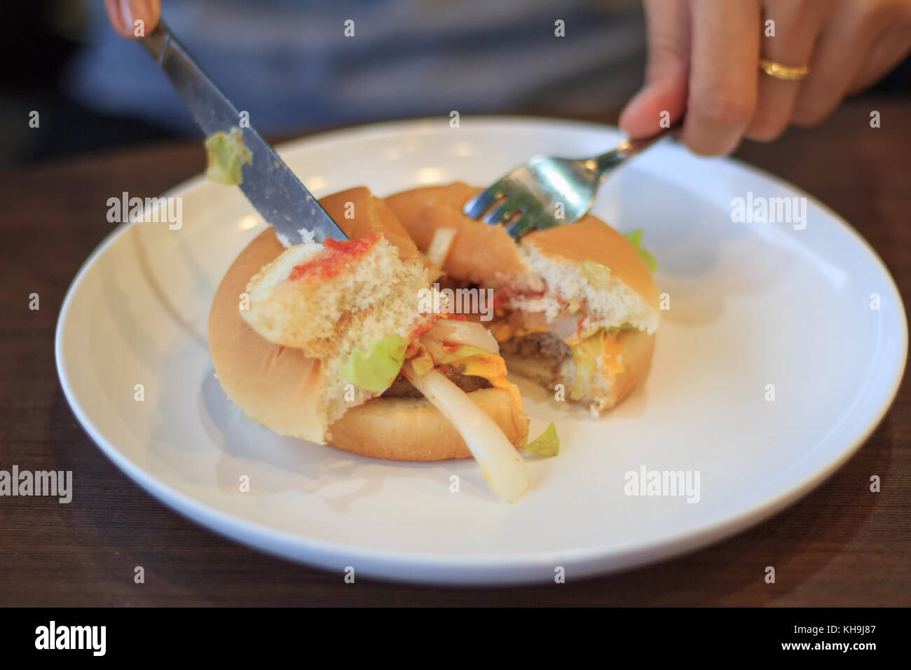 Close-up burger di taglio blured o sfocature soft focus, tenendo burger tagliata in due halfs blured o sfocature soft focus, formaggio hamburger, giovane donna burge di taglio Foto Stock