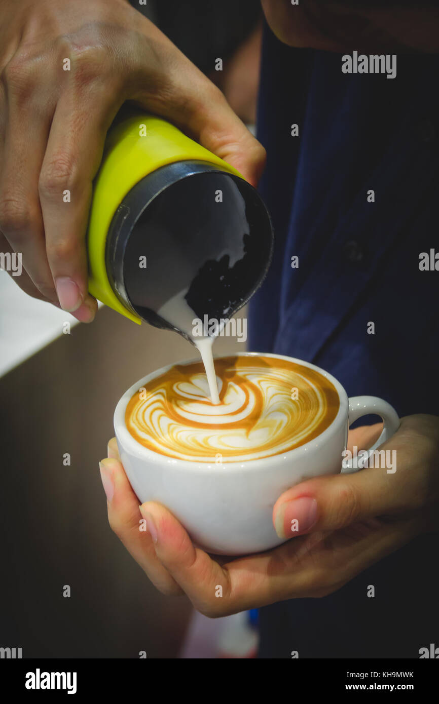 Barista versando il latte dal lanciatore per una tazza di caffè latte art Foto Stock